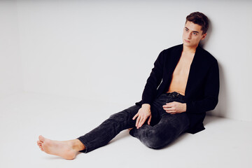 Man in black jacket sitting on the floor fashion modern style glamor portrait isolated background