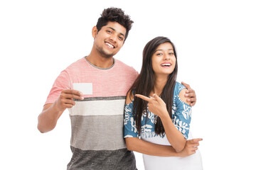 Fototapeta premium Cheerful young Indian couple holding business card on white.