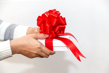 Hand of a young woman holding a white gift box with a red ribbon And the hand of the child extended to meet him Various important day gift ideas such as New Year, Christmas, Valentine on a white backg
