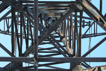 Fototapeta premium High voltage transmission tower line against blue sky, bottom view. iron construction.
