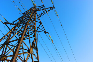 High voltage transmission tower line against blue sky, bottom view. iron construction.