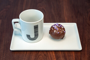 Close up food photograph of a hot cocoa bomb covered in drizzled brown chocolate and purple and...