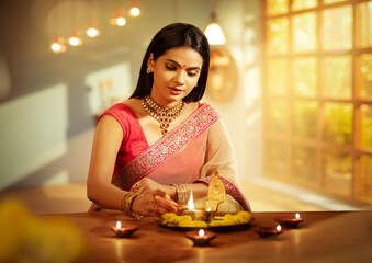 Beautiful Hindu Indian young women lightening Diya on Diwali day.