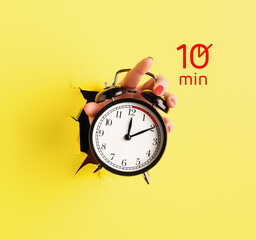 Female hand holding alarm clock with timer for 10 minutes on color background. Time management...