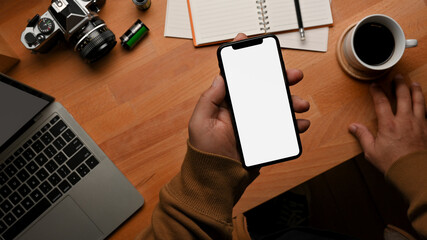 Top view of male hand holding smartphone on worktable
