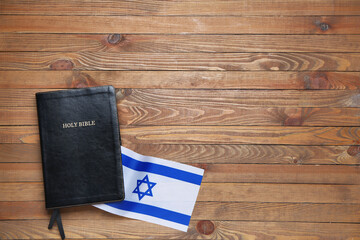Holy Bible and flag of Israel on wooden background