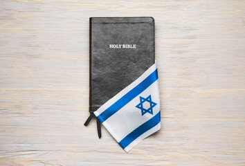 Holy Bible and flag of Israel on light background