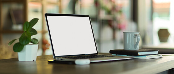 Portable workspace with laptop, stationery and supplies on wooden table in cafe