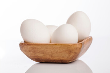 Wooden cup of white eggs on white background.