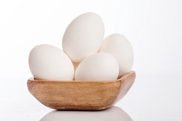 Wooden cup of white eggs on white background.