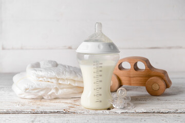 Bottle of milk for baby with accessories on table - obrazy, fototapety, plakaty