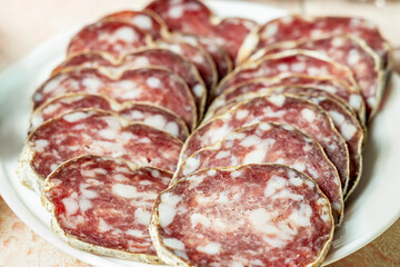 Dried sausage sliced ​​on a white plate close-up. Shallow depth of field.