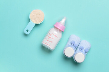 Bottle of baby milk formula and booties on color background