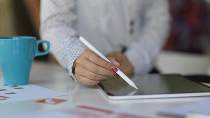 Female using digital tablet with stylus pen on meeting table