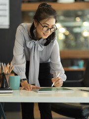 Businesswoman working with digital tablet while standing at office desk