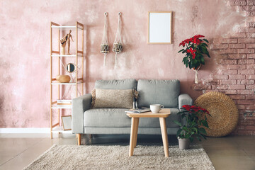 Stylish interior of room with sofa and poinsettia plants