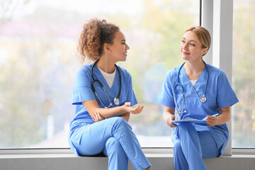 Female doctors sitting on window sill in clinic