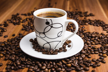 Cup of coffee with coffee beans at wooden background.