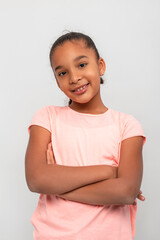 Studio shot of a dark skinned smiling girl wearing pink shirt  against grey background