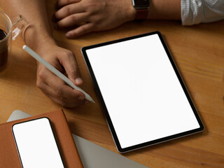 Businessman using digital tablet on wooden table with notebook and smartphone