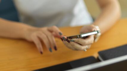 Obraz na płótnie Canvas Female hands touching on smartphone on workspace