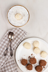 Homemade Indian round vegetarian sweets. Coconut and cocoa balls in a white bowl with coconut shavings