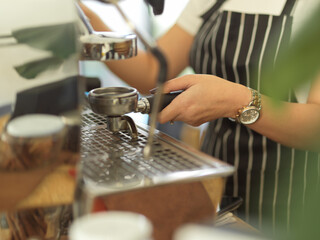 Female barista hand working with coffee machine in cafe