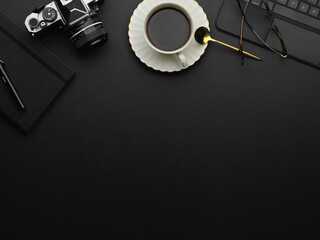 Top view of copy space on black table with coffee cup, camera and supplies