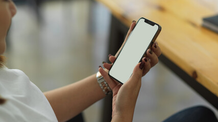 Side view of female hands holding smartphone while sitting in office room