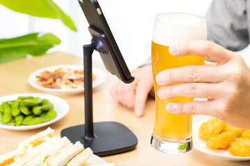 スマートフォンでリモート飲み会をする男性