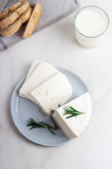 Adyghe cheese is cut into pieces on a gray plate. Soft goat cheese