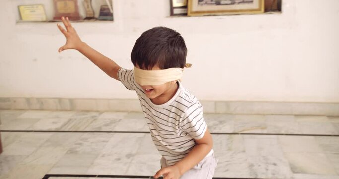 Slow-motion portrait of a young male child blindfolded as he walks around playing hide and seek but there is no one home 