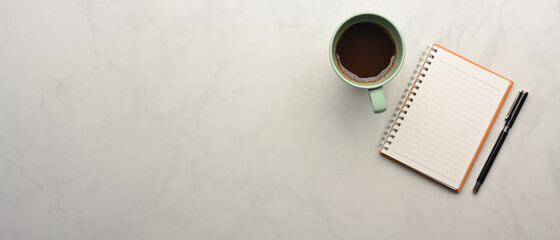 Worktable with notebook, pen, coffee cup and copy space on marble desk