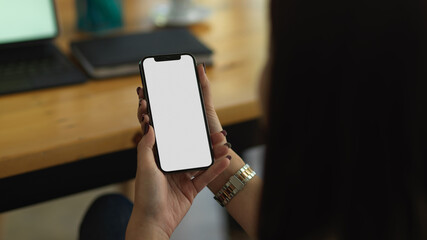 Female hands holding smartphone while sitting in office room