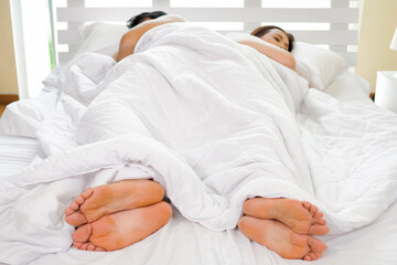 Asian couple lying together on the bed. Focus on hands man and woman.