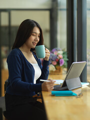 Female university student take a coffee break while doing assignment