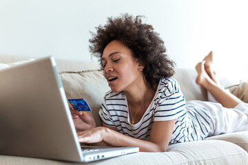 Female consumer spending buying on internet, lifestyle. Happy woman shopping online with laptop at home. Woman using laptop computer shopping on line, using credit card playing online, smiling indoors