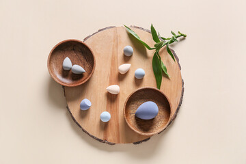 Board with makeup sponges on light background