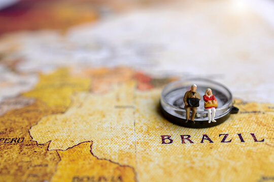 Miniature people: traveling with a backpack sitting on compass and vintage world map,  Travel, vacation and summer concepts.