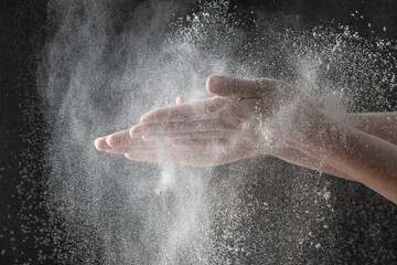 Fototapeta na wymiar wave of hands with flour on a black background