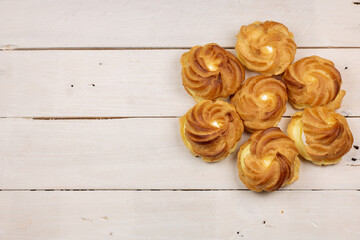 Profiterole puff dessert with yolk cream and egg white sweet filling. Served on old retro vintage wooden white table.  Wedding cake. Space for text. Top view