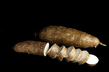 One whole yucca and one cut into slices on black background
