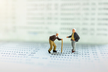 Miniature people stand on the bank passbook, Retirement planning and life insurance concepts.