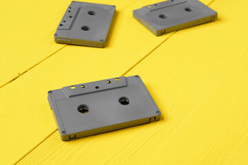 Gray audio cassettes on yellow background top view