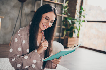 Portrait of sweet optimistic girl sit write notebook wear spectacles pijama at home