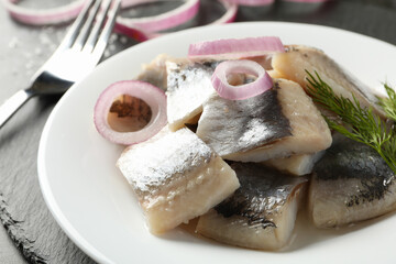 Black tray with plate of fresh herring fish slices
