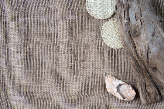 Wicker straw stands, bast shoes and wooden snag on gunny background. Flatlay, topview, copyspace, minimalism, natural eco concept