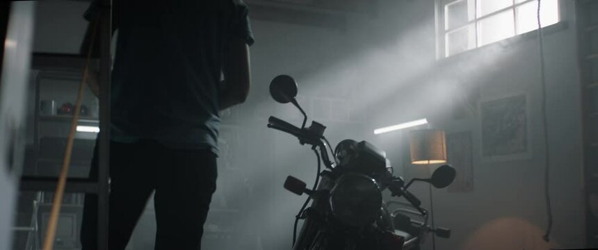 Caucasian male performing maintenance of his vintage motorcycle at home garage. Shot with 2x anamorhpic lens