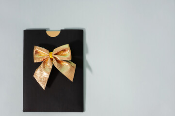 Black envelope with a golden bow on gray. Gift concept. Trending concept. Copy space. Top view