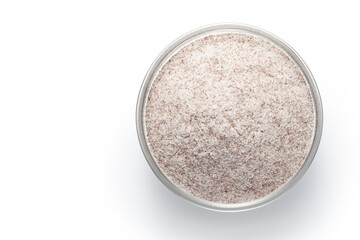 Black whole wheat flour in a glass bowl isolated on white background. Top view.